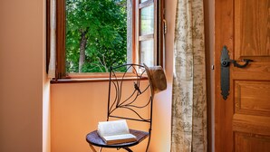 Une chaise avec un livre, une fenêtre donnant sur des arbres et une porte en bois.