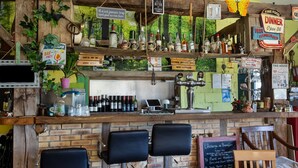 Un espace bar avec des étagères en bois, des tabourets de bar et diverses bouteilles.