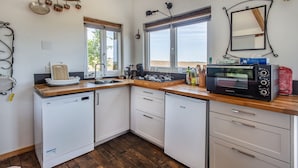 Une cuisine avec des meubles blancs, un four à micro-ondes, un évier et une fenêtre donnant sur un beau paysage.