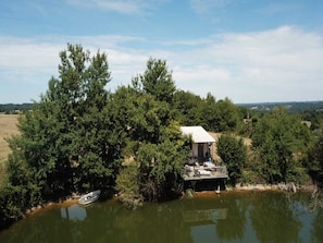 Eine Holzhütte am Seeufer mit einer Terrasse, umgeben von dichtem Wald und einem angestoßenen Boot.
