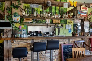A bar area with wooden shelves, bar stools, and various bottles. - Caravan 'Vue Sur L'étang' with Lake View, Shared Pool and Private Terrace (Champsac)