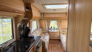 Ein kompaktes Wohnmobil-Interieur mit Küchenzeile, Essbereich und Sitzgelegenheit.
