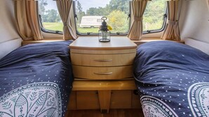 Ein Schlafzimmer mit einem Bett, einer hölzernen Kommode und einem Fenster mit Vorhängen.