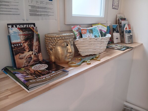 A reception desk with magazines, a Buddha statue, and a decorative bowl.