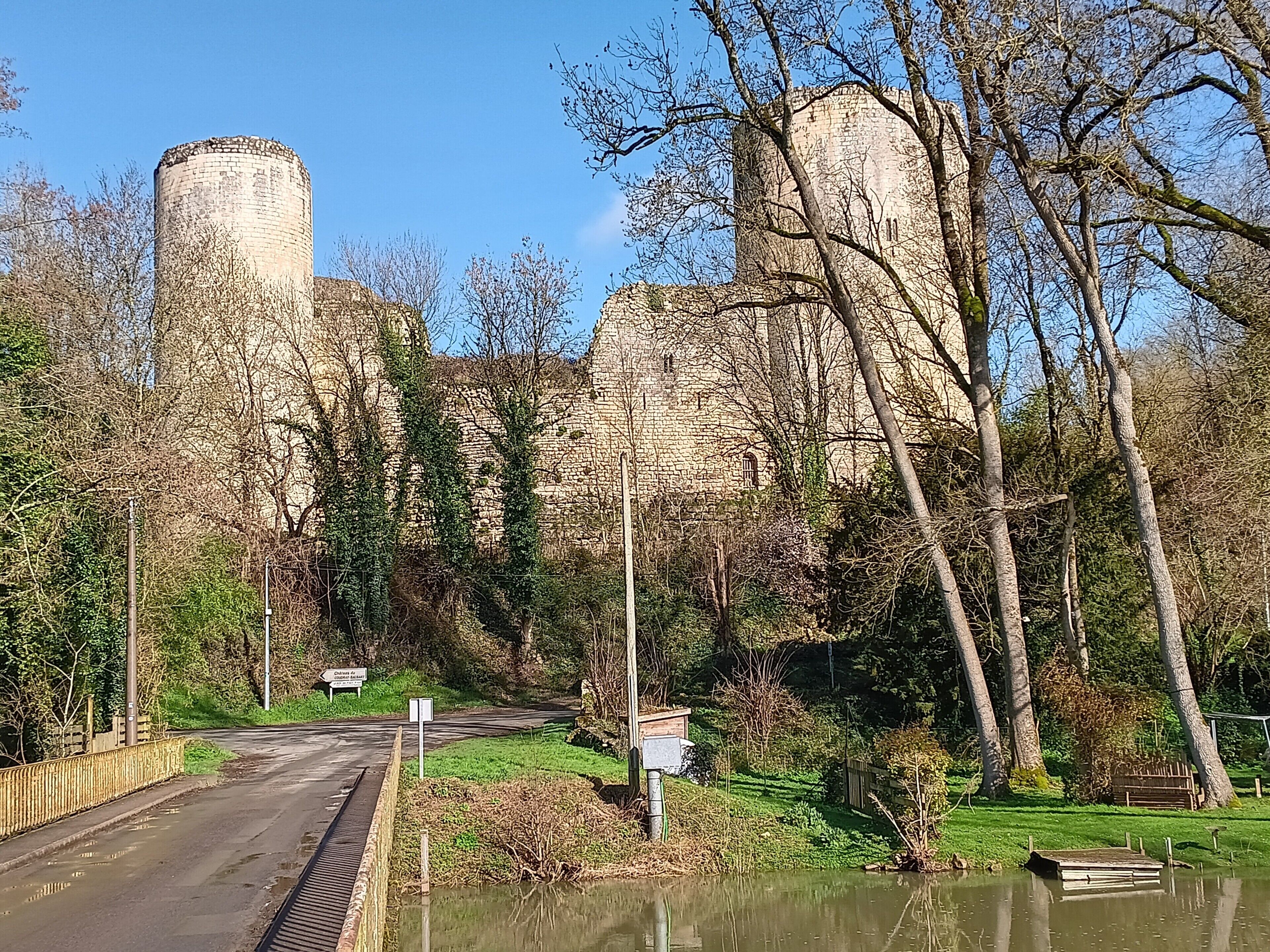 A historic stone tower, a paved road, and a body of water with a wooden dock.