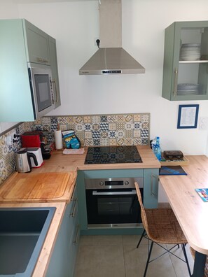 Una cocina compacta con horno integrado, estufa y microondas.