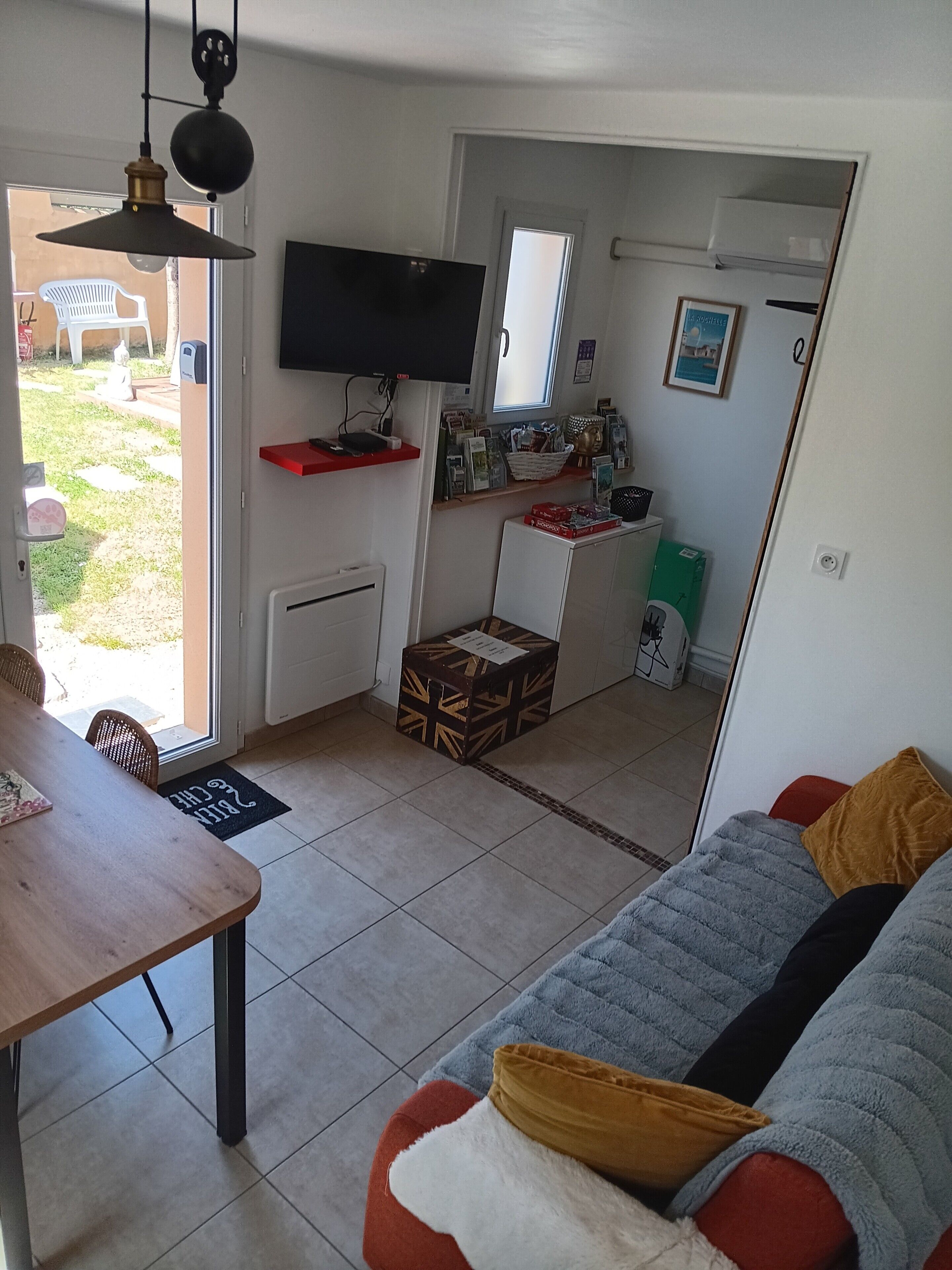 A compact living space with a kitchenette, a dining area, and a seating area with a sofa and ottoman.