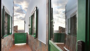 A narrow corridor with green doors and windows, stone walls, and a tiled floor. - Holiday Home 'Casa Dayaday' with Mountain Views and Wi-Fi (Puerto del Rosario)
