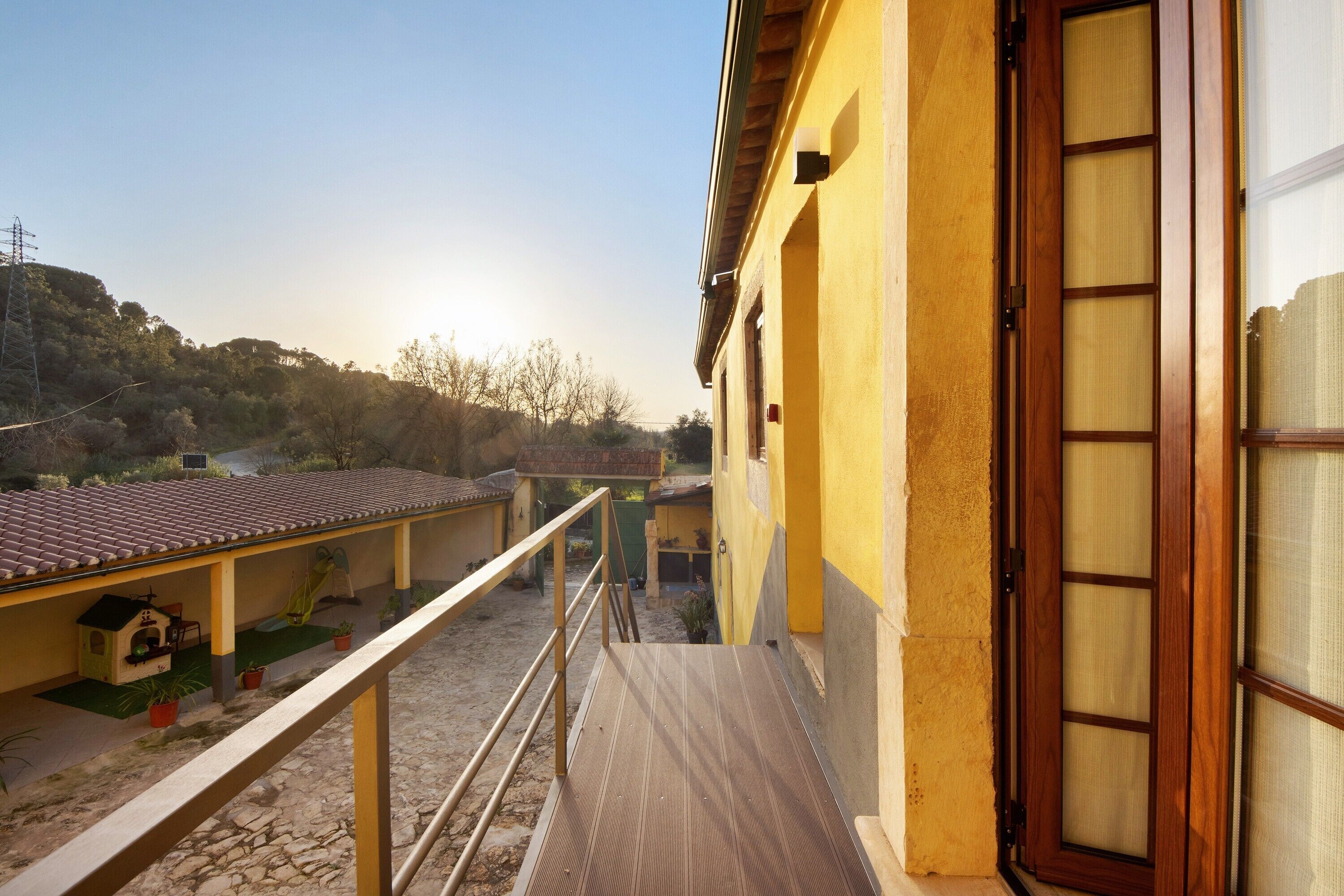 Ein Gebäude mit gelber Fassade, einer Holztür und einem Balkon mit Metallgeländer.