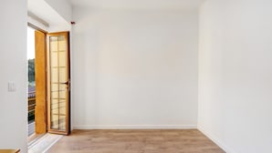 Una stanza con pavimento in legno, pareti bianche e una porta scorrevole in vetro che dà su uno spazio all'aperto.
