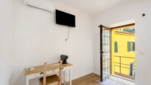 A room with a desk, chair, television, and a sliding glass door leading to an outdoor area.