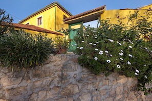 Un edificio amarillo con un muro de piedra y una puerta verde.