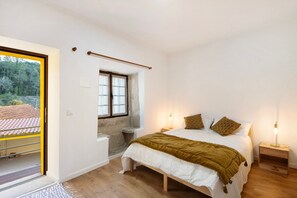 Un dormitori amb un llit, taules de nit, una finestra i una porta que dona a una zona exterior.