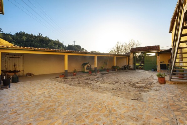 A courtyard with a cobblestone floor, yellow walls, and potted plants.