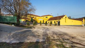 Un edificio amarillo con valla verde, una calle pavimentada y cielo despejado.