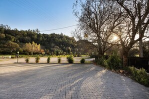 Un sendero pavimentado que lleva a un área de estacionamiento, con árboles y un paisaje montañoso al fondo.