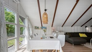 Un coin repas avec une table dressée pour quatre personnes, un canapé et un luminaire suspendu.
