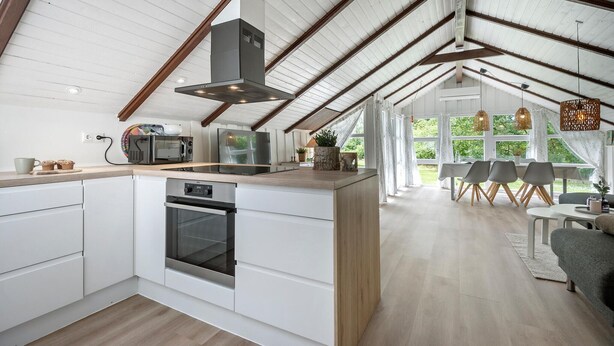 Une cuisine moderne avec des meubles blancs, un four encastré et un grand îlot central.