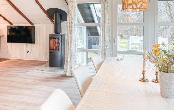 A modern living room with a fireplace, a dining table with chairs, and a TV mounted on the wall.