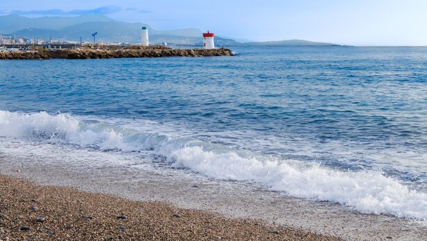 Eine Küstenansicht mit Leuchtturm, felsigem Ufer und ruhiger See.