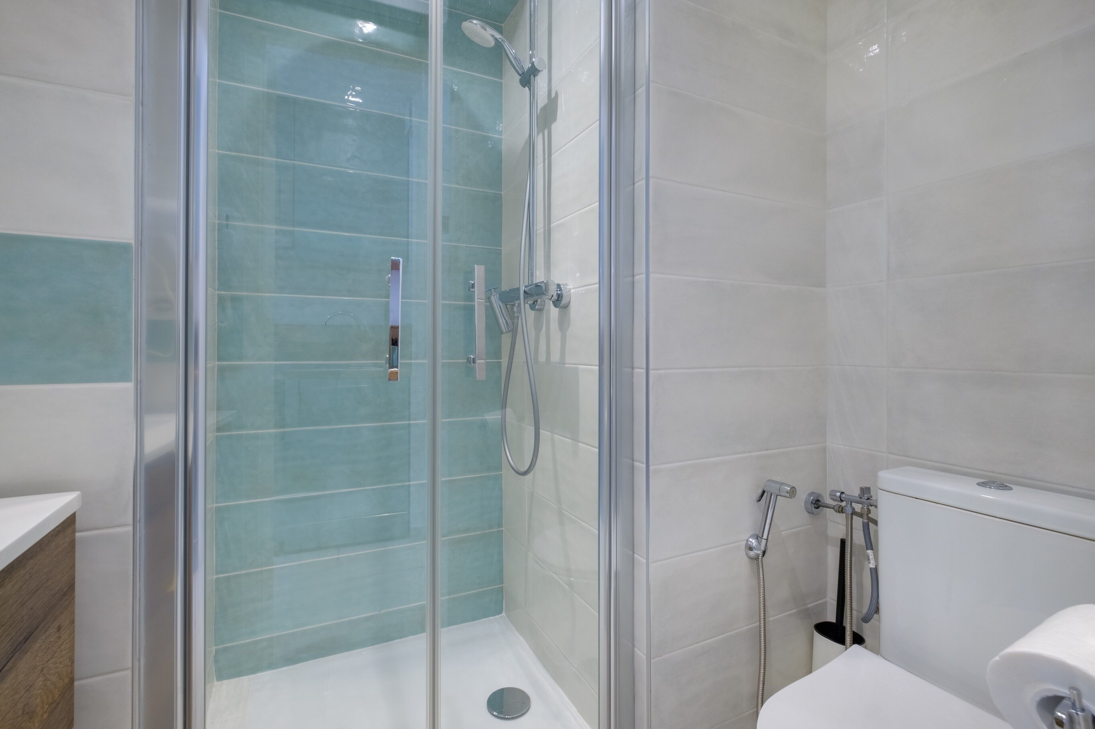 Une salle de bain moderne avec une douche à parois de verre, des carreaux blancs et des toilettes.