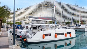 Ein Yachthafen mit Booten, vor einem großen, mehrstöckigen Hotel mit Balkonen.