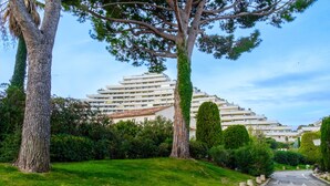 A residential building with a modern design, surrounded by well-maintained greenery and a clear sky.
