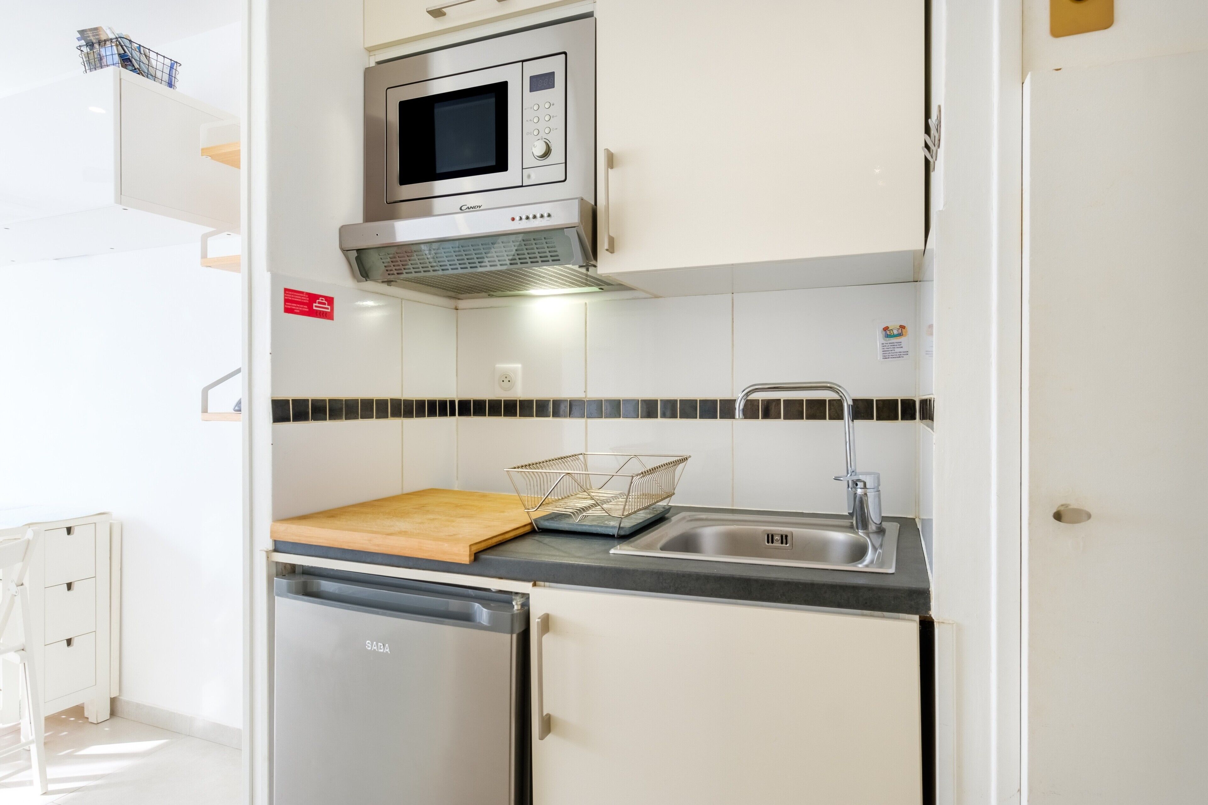 Une cuisine compacte équipée d’un four à micro-ondes, d’un évier et d’un lave-vaisselle.