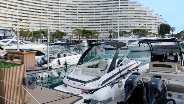 A marina with boats docked, a large hotel building in the background, and a wooden structure labeled 'NAUTIC EVASION'.
