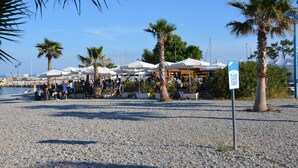 A beachside area with outdoor seating, palm trees, and a sign indicating no swimming.