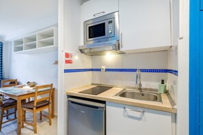Una cucina compatta con forno a microonde, lavello e lavastoviglie.