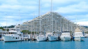 Un port de plaisance où sont amarrés de nombreux bateaux, devant un grand hôtel à plusieurs étages doté de balcons.