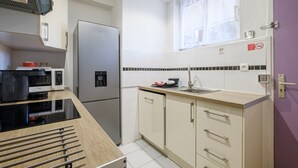 A compact kitchen with a refrigerator, microwave, and a sink. - Studio Apartment 'Venus - Rdc - 2 Couchages Doubles' with Wi-Fi and Air Conditioning (VILLENEUVE LOUBET)