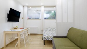 A small room with a bed, a desk with a chair, a television, and a window with curtains. - Studio Apartment 'Venus - Rdc - 2 Couchages Doubles' with Wi-Fi and Air Conditioning (VILLENEUVE LOUBET)