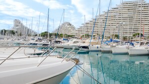 A marina with multiple boats docked, a large hotel building in the background, and clear skies. - Studio Apartment 'Venus - Rdc - 2 Couchages Doubles' with Wi-Fi and Air Conditioning (VILLENEUVE LOUBET)