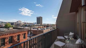 A balcony with wicker chairs, a view of a cityscape including a tall building labeled 'BBVA,' and a brick building in the foreground.