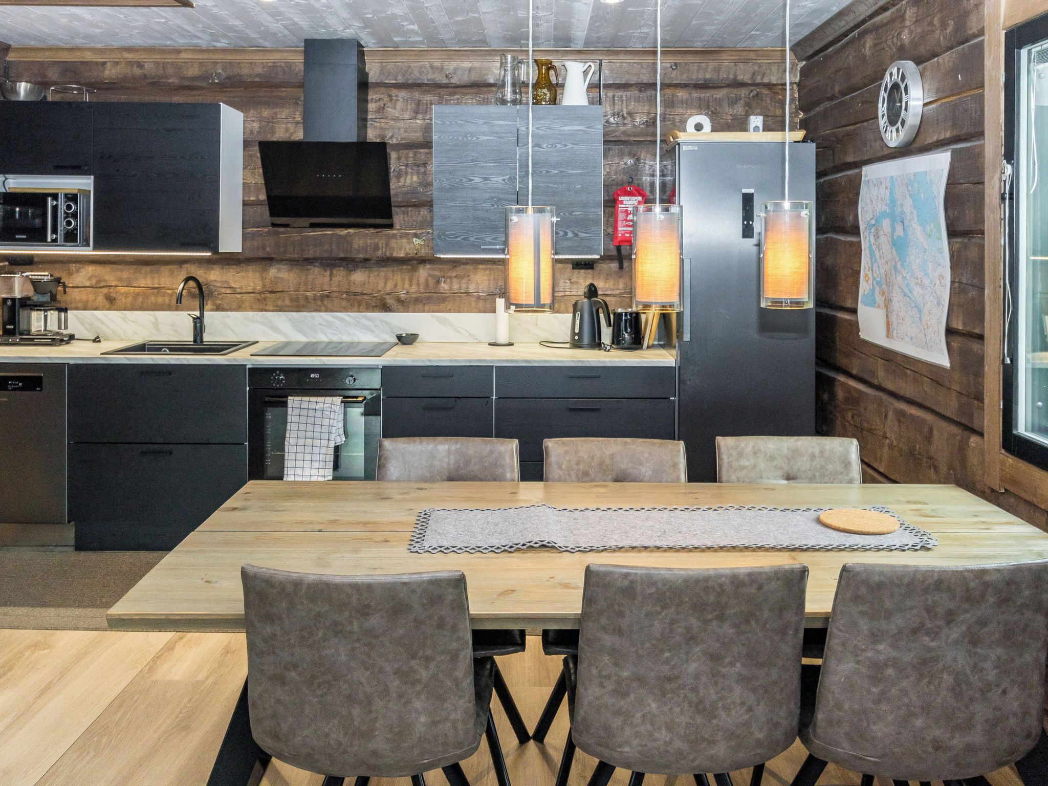 A modern kitchen with a dining area, wooden walls, and a large window.
