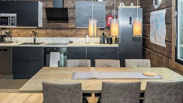 A modern kitchen with a dining area, wooden walls, and a large window.