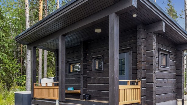 A log cabin with a porch, two windows, and a small deck area.