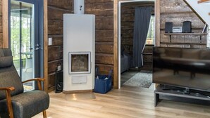 A cozy living room with a wood-burning stove, a comfortable chair, and a flat-screen TV.