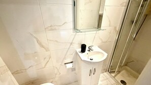 A bathroom with a toilet, sink, and glass shower enclosure.