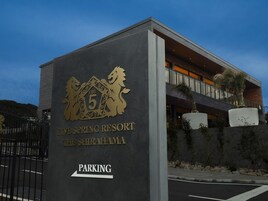 Exterior del resort Five Spring, con un llamativo emblema de león y un cartel que indica la zona de estacionamiento.