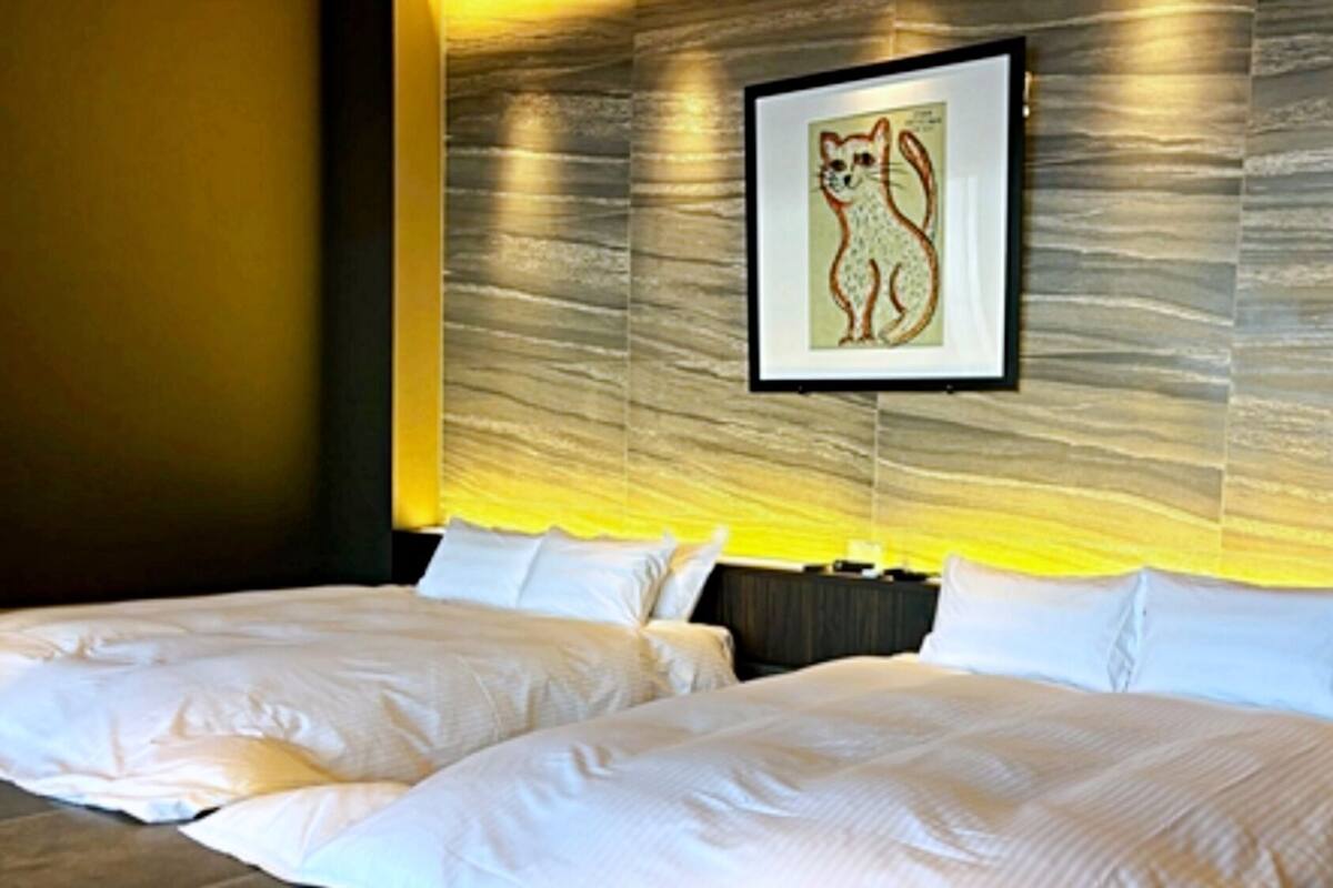A hotel room with two beds, a framed picture on the wall, and a textured wall design.