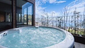 Ett bubbelbad med utsikt över havet och den omgivande vegetationen.