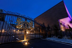 Una entrada cerrada con una estatua de león y el número 5, que conduce a un edificio de diseño moderno con ventanas iluminadas.