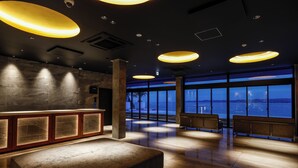 En modern entréhall med stora fönster, en receptionsdisk och en sittgrupp.