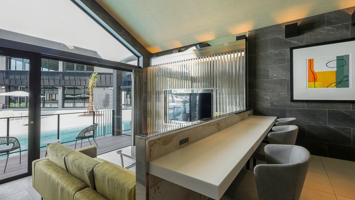Un espace bar moderne avec vue sur la piscine, un canapé et un tableau abstrait encadré.
