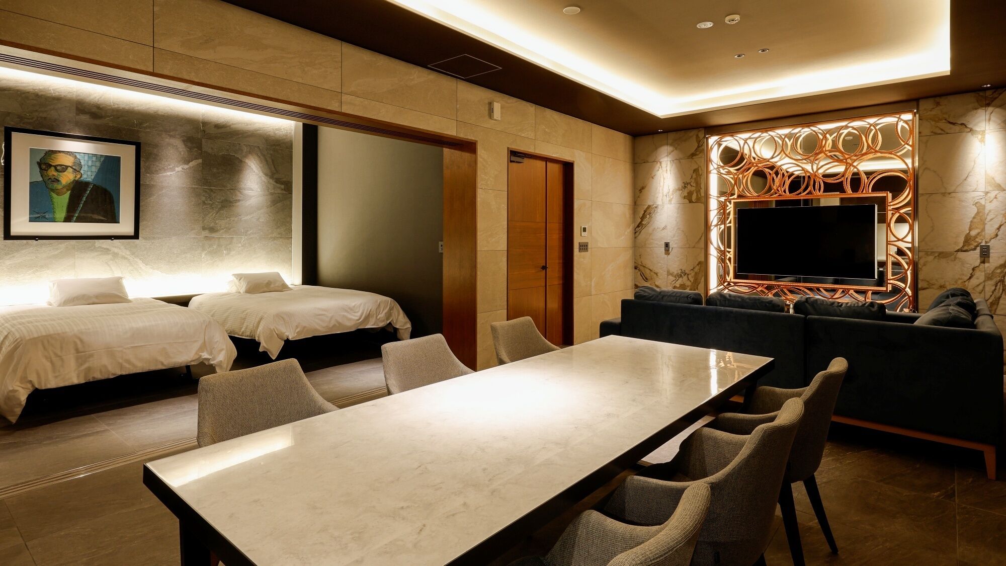 Ein Hotelzimmer mit zwei Betten, einem Esstisch, einer Couch und einem Fernseher.