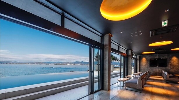 En modern hotellobby med en stor glasvägg som ger utsikt över havet.