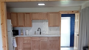 A spacious kitchen with wooden cabinets, a central island, and a herringbone-patterned backsplash.